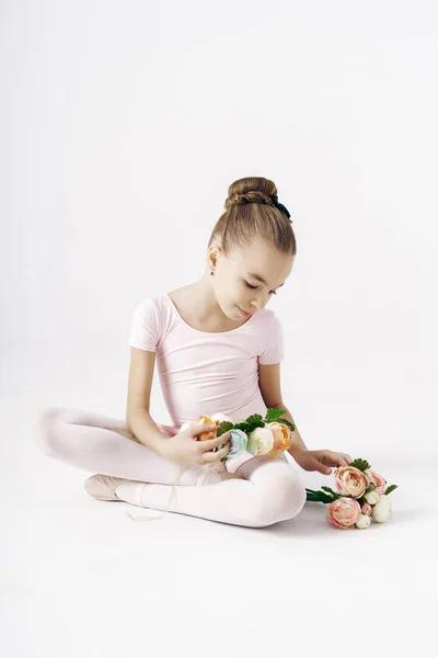 Красива дівчина балерина позує з квітами на білому тлі — стокове фото