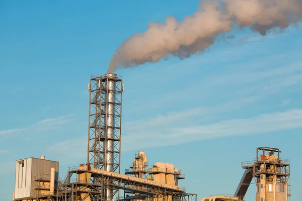 Промышленное предприятие с дымовым выхлопом из трубы на голубом фоне неба — стоковое фото