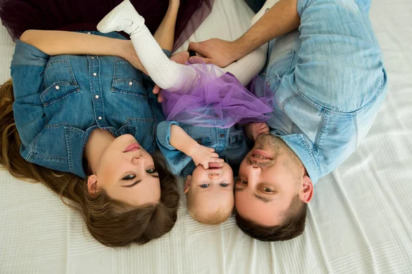 Belle famille moderne en robe denim couchée sur le lit — Photo