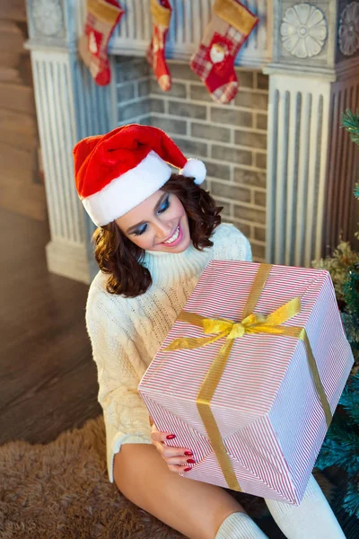 お祝いのエレガントなクリスマス ツリーの近くの赤い帽子の美しい細長い幸せな若い女の子 — ストック写真