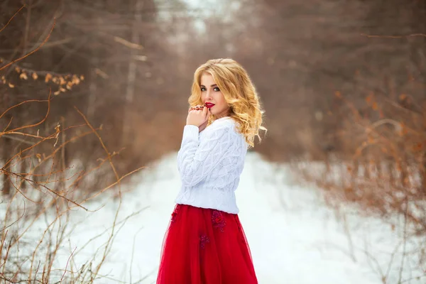 一个美丽的年轻金发女孩的肖像户外在寒冷的天气穿着白色毛衣晒太阳 — 图库照片
