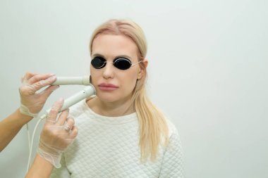 güzel genç kız bir güzellik salonda bir uzmanla yüz gençleştirme işlemleri yapıyor