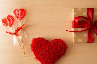 güzel bir şekilde dekore edilmiş hediye ile dekore edilmiş kalp ve lolipop hafif ahşap bir arka plan üzerinde kırmızı bir yay ile bir kutu içinde