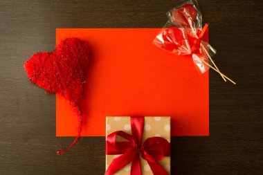 güzel bir şekilde dekore edilmiş hediye kutusunda ve dekore edilmiş kalp ve lolipop ahşap koyu arka plan üzerinde kırmızı bir yayla