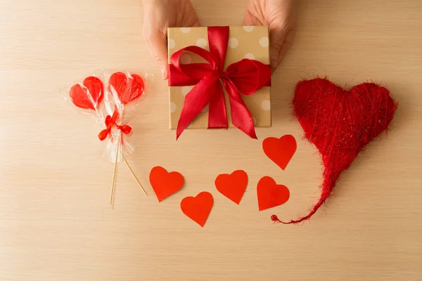 美丽的装饰在一个盒子与装饰的心和木质轻棒的背景下的红弓的礼物 — 图库照片