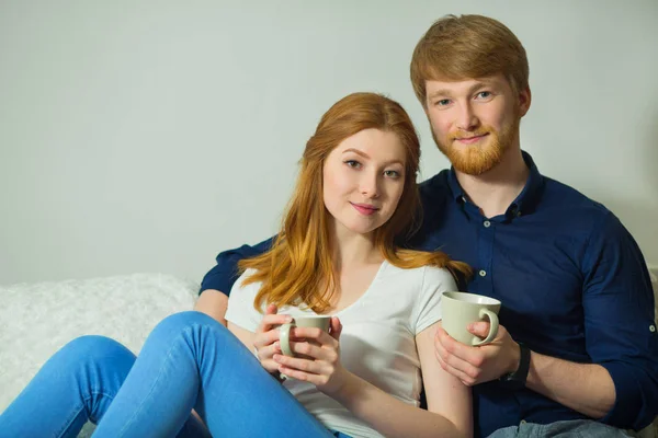 ソファに座って お茶を飲んで赤い髪の少女と美しい若いカップルの男 — ストック写真