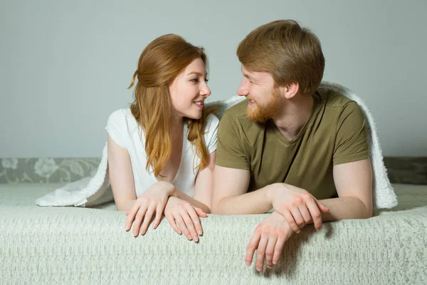 毛布の下のソファーで横になっている赤い髪の少女の幸せな若いカップルの男 — ストック写真