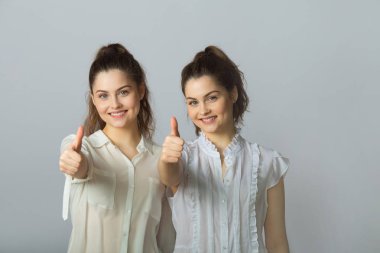 hareketleri başarı gösteren hafif bir arka plan üzerinde beyaz bluz içinde iki güzel gülümseyen kız kız kardeş ikiz