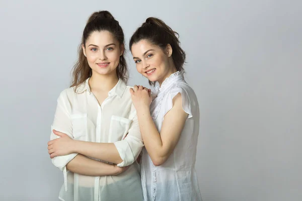 Две Красивые Улыбающиеся Девушки Близнецы Белых Блузках Светлом Фоне — стоковое фото