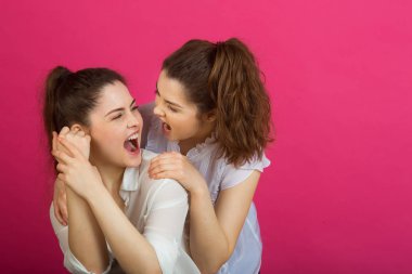 iki güzel genç kız ikiz iyi bir ruh hali içinde pembe bir arka plan üzerinde beyaz bluz