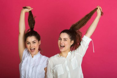 iki güzel neşeli genç kız kız kardeş kız pembe bir arka plan üzerinde yüzleri duygusal ifadeleri ile jest