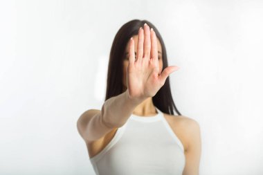 bir mola belirten bir el bir hareketi ile yüzünde ciddi ve dalgın bir ifade ile beyaz bir arka plan üzerinde beyaz kolsuz bluz siyah saçlı güzel genç ciddi kız