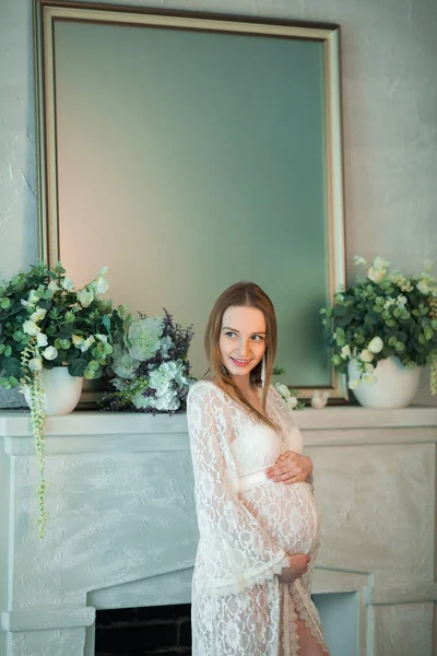 Güzel Genç Hamile Kız Bir Şömine Duran Beyaz Dantel Elbise — Stok fotoğraf