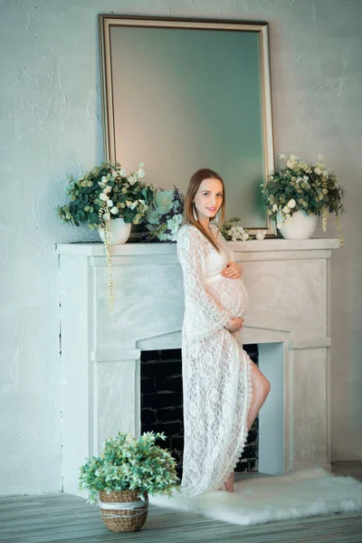 Güzel Genç Hamile Kız Bir Şömine Duran Beyaz Dantel Elbise — Stok fotoğraf