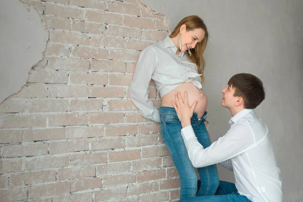 Belo Marido Mulher Grávida Jeans Camisa Branca Perto Parede Branca — Fotografia de Stock