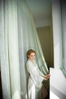 Beyaz dantel soyunma ayakta pencere yakınındaki güzel genç gelin