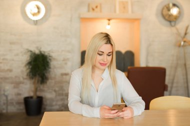 güzel genç kızla Beyaz gömlekli kafede otururken elinde telefon