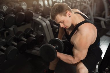 yakışıklı genç eğitim salonunda dumbbells ile