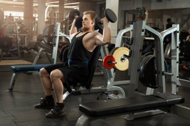 yakışıklı genç eğitim salonunda dumbbells ile