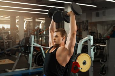 yakışıklı genç eğitim salonunda dumbbells ile