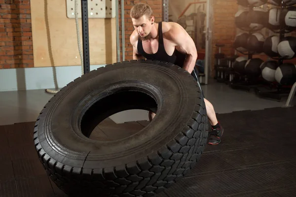 有胡子的漂亮男人在健身房里拉着一个沉重的轮子 — 图库照片