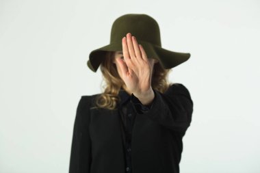 Beyaz bir arka planda bir stop belirten bir el hareketi ile şapkalı güzel genç kız