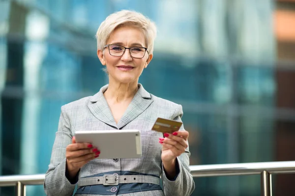 beautiful stylish woman with a short haircut in a suit with a tablet and a credit card in her hands