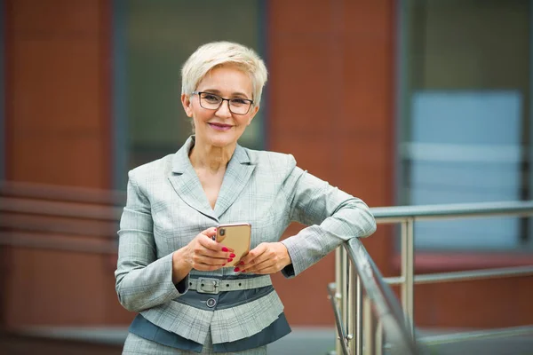 beautiful stylish woman with a short haircut in a suit with a phone in her hand