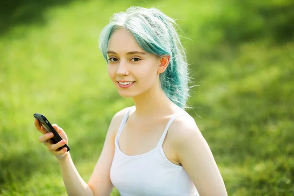 公園の屋外で携帯電話を手にスポーツウェアを着た美しい若い女性が — ストック写真
