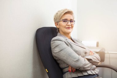 Takım elbiseli yetişkin bir kadın ve kapalı bir masada gözlük.