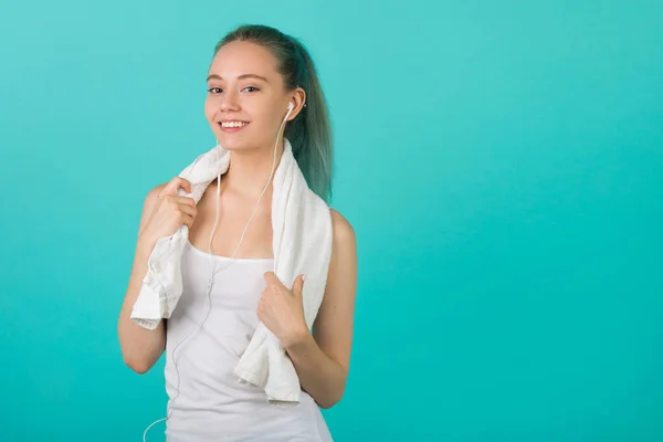 beautiful young slim woman in sportswear on a blue background listens to music