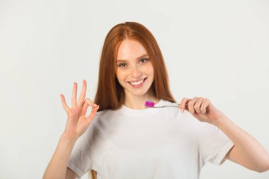 Beyaz tişörtlü, elinde diş fırçası olan güzel bir kadın.