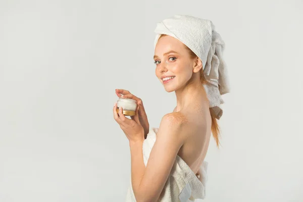 白いタオルにクリームを手にした美しい若い女性が — ストック写真