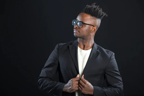 handsome african man in a suit with glasses on a black background