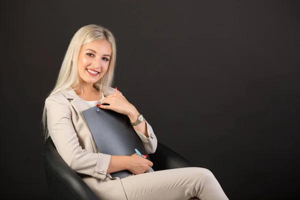 beautiful young woman in a suit on a black background with a folder