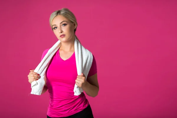 ピンクの背景にタオルを肩につけたスポーツウェアを着た美しい若い女性 — ストック写真