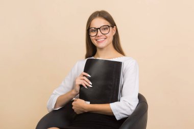 Gözlüklü, elinde klasörle güzel bir genç kadın.