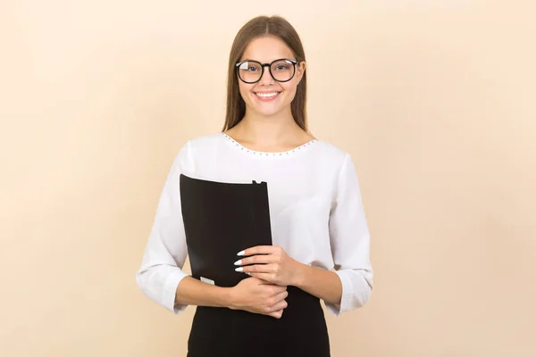 漂亮的年轻女子戴着眼镜 背景是米色的 手里拿着文件夹 — 图库照片