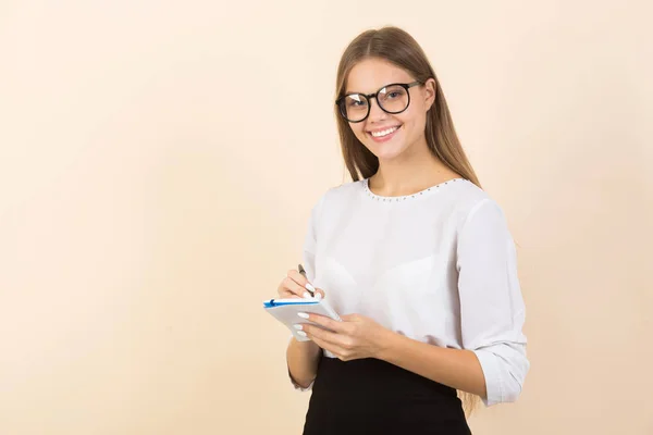 Bej arka planda gözlüklü, not defterli güzel bir kadın.