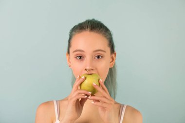 Spor giysili güzel, narin genç bir kadın elmayı ısırıyor.