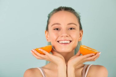 Güzel, narin, spor giyimli, elinde portakallarla genç bir kadın.