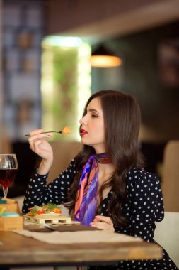 Güzel genç bir kadın bir restoranda yemek yiyor.