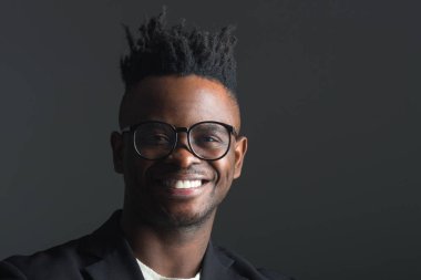 Gri arka planda siyah takım elbiseli yakışıklı Afrikalı adam.