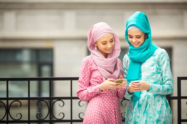 Dua Wanita Muda Yang Cantik Berpakaian Muslim Dengan Ponsel Tangan — Stok Foto