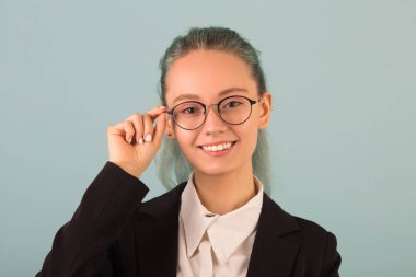 Gözlüklü güzel bir kadın ve gri arka planda siyah bir takım elbiseli.