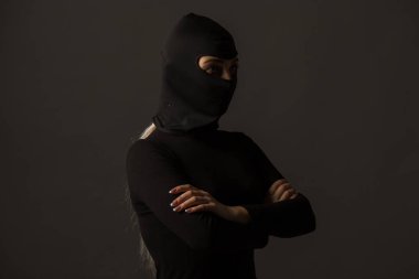 Gri arka planda siyah maskeli kimliği belirsiz bir kadın.