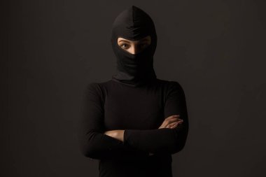 Gri arka planda siyah maskeli kimliği belirsiz bir kadın.