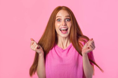 Pembe arka planda el hareketleriyle kızıl saçlı güzel bir genç kadın.