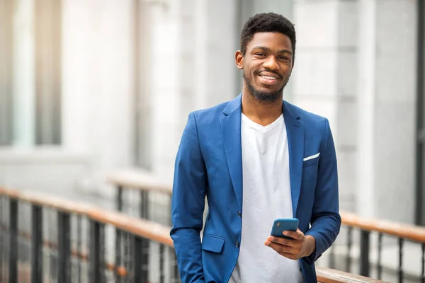 Elinde telefon olan mavi ceketli yakışıklı bir Afrikalı.