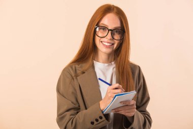 Bej arka planda ceketli, kızıl saçlı güzel bir kadın.